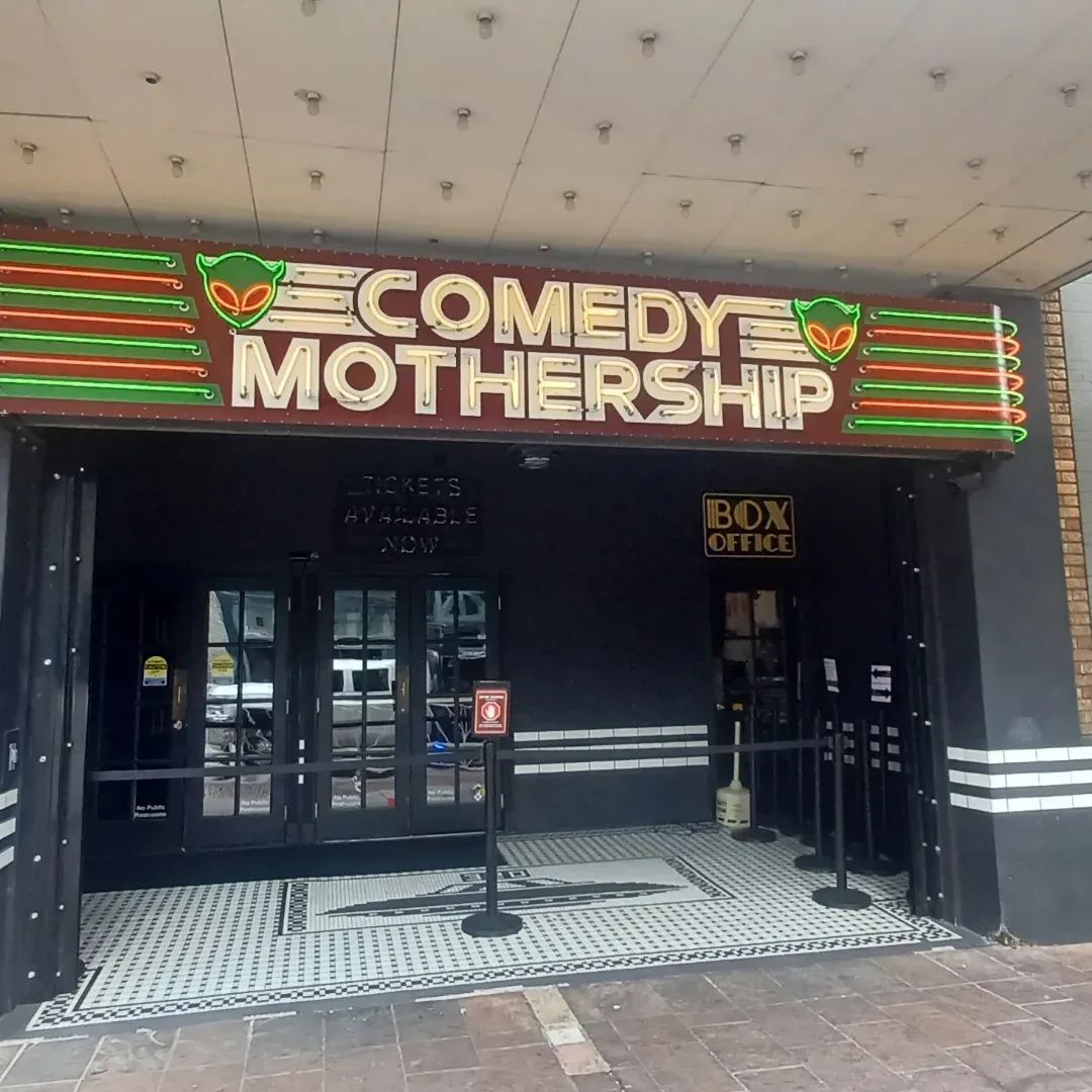 Exterior of the Comedy Mothership comedy club with its neon marquee.