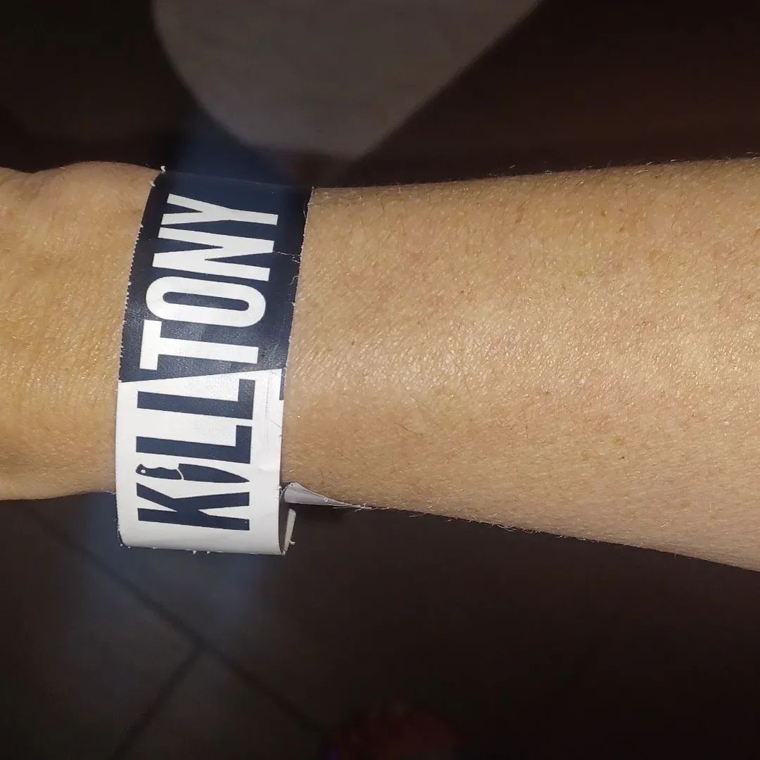 Close-up of a comedy show wristband worn on the wrist.